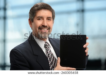 Mature Businessman holding an electronic tablet inside an office building