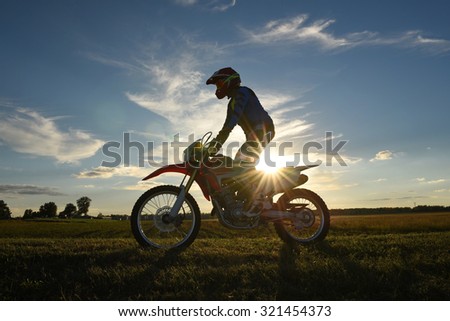 Motocross rider in the country side with sunset on background