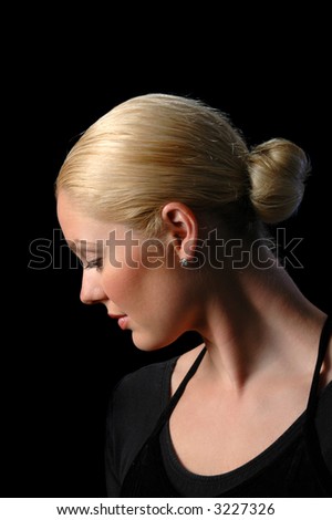 Ballerina\'s profile looking down against a black background