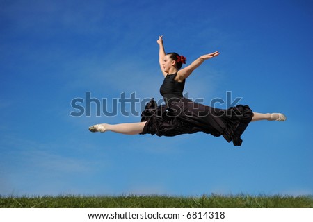 Dancer jumping on grass against a blue sky