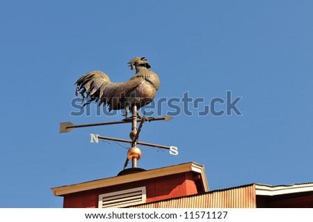 Weather vane shaped like a rooster against clear sky