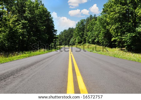Road in a rural area with trees and blue sky