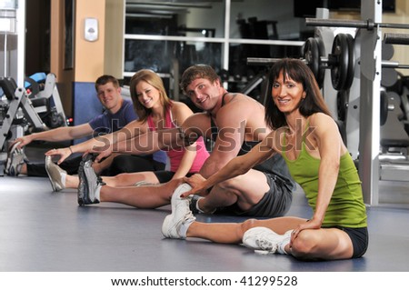 Group of people stretching at the gym with focus on the trainer on the foreground