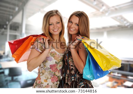 Two Beautiful Young Women holding colorful shopping bags inside  a Mall
