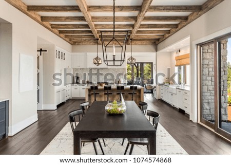 Stunning Dining room and Kitchen in New Luxury Home. Wood beams and elegant pendant lights accent the beautiful open floor plan, dining room, and kitchen.
