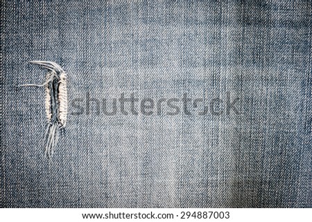 Close-up of a ripped and frayed section of well-worn denim.