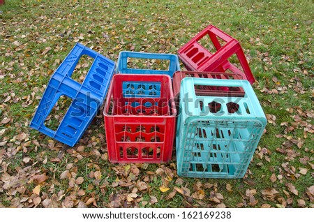 colorful empty plastic boxes for beer bottles on autumn meadow