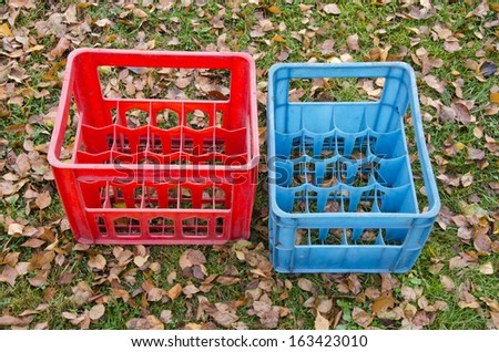 two empty plastic boxes for beer bottles on autumn meadow