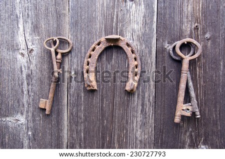rusty ancient key and vintage horseshoe collection on old wooden barn wall