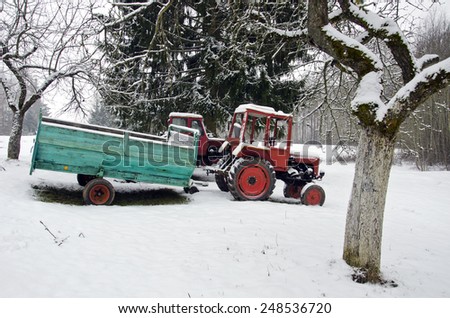 old small agriculture tractor in winter farm garden on snow