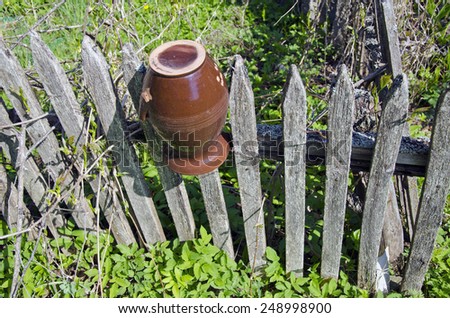 Old broken brown jar on  farm wooden fence