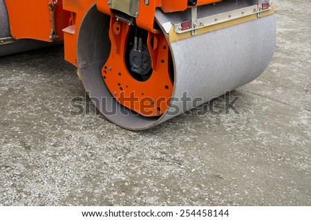 small orange road roller machine on city park track