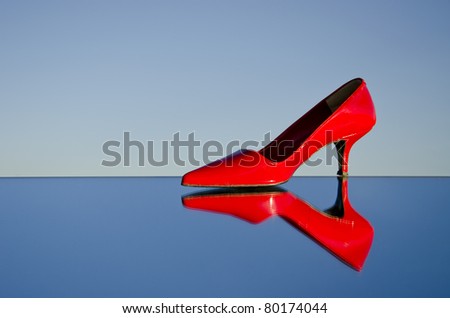 one red stiletto on mirror and sky background