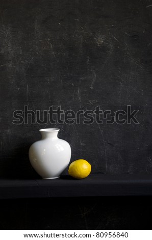 white vase and yellow lemon on black background