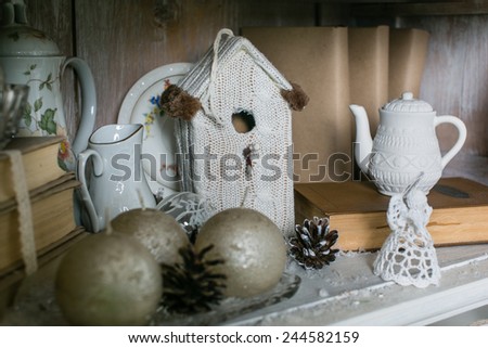 Winter decor with old books, vintage kitchenware, thick candles, pine cones and a knitted toy angel