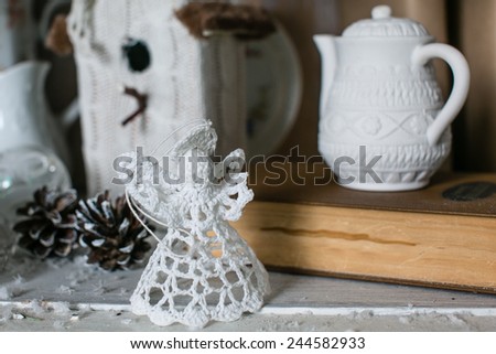 Christmas winter decoration with old books, vintage kitchenware, candles, pine cones and knitted angel