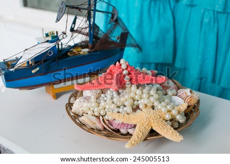Beautiful starfish and pearl beads in a basket and decorative boat