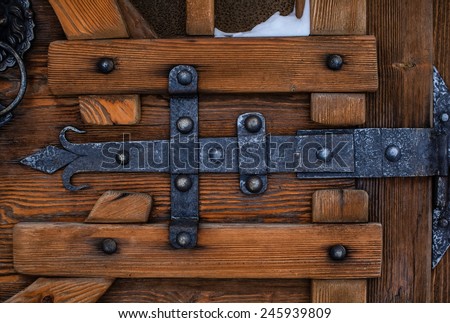 Heavy metal bolt on a wooden door, artistic forging