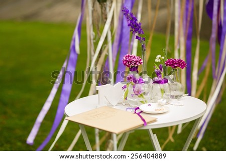 White table for visiting ceremony with the decor and purple flowers on a background of a wedding arch