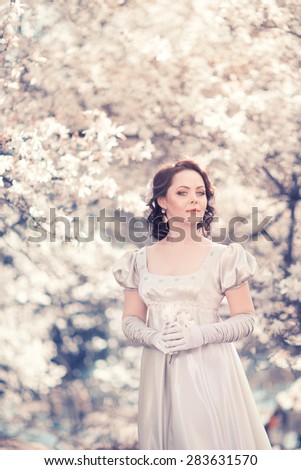 Beautiful girl in vintage satin dress in the lush spring garden magnolia