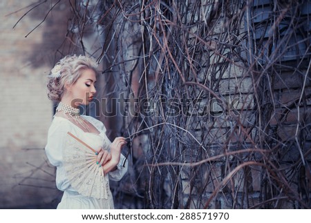 Beautiful blonde in an old white satin dress, a mysterious atmosphere, loneliness, mystery
