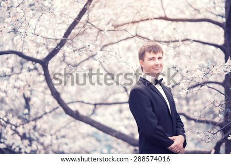 Portrait of the groom in a lush garden, wedding day