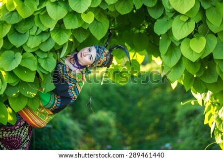 Beautiful young woman of Asian appearance in bright national costume in nature, summer, tropics