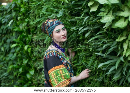 Beautiful young girl in colored clothes on a bright background of tropical nature, summer heat