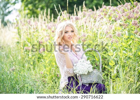 Beautiful blonde girl in a flowering field, summer heat