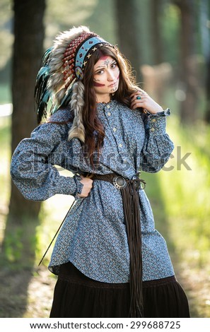 Beautiful young Indian woman in a blue shirt and national headdress of feathers