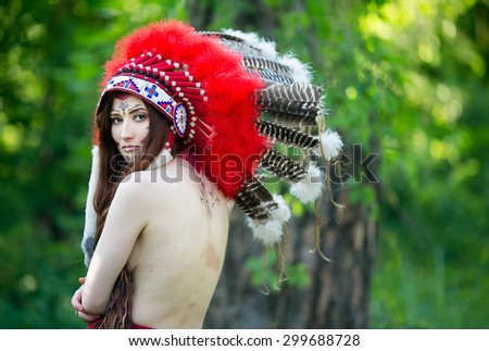 A beautiful Indian woman in a national headdress of red feathers and naked back