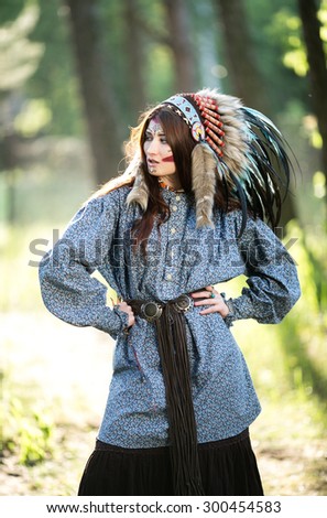 Beautiful young Indian woman in a blue shirt and national headdress of feathers