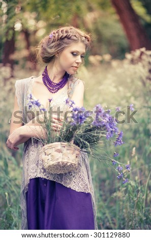Young beautiful girl with a basket of cornflowers in a charming rustic dress