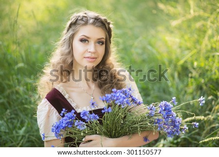 Beautiful girl in a vintage dress holding a rustic basket with bright blue cornflowers. summer, garden, village, sunset