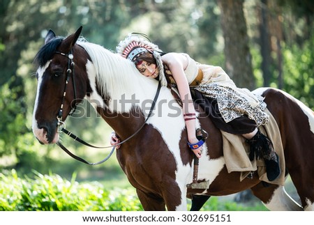 Portrait of a beautiful young woman dressed in indian national dress, tired, lying on the horse, forest
