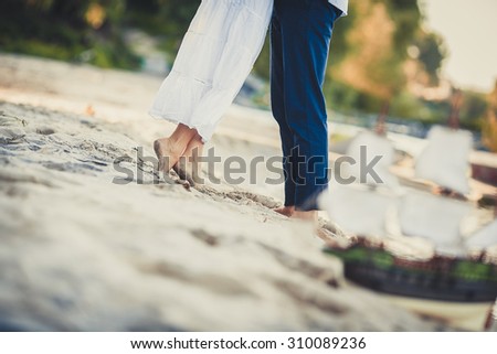 Man and woman embracing on the background of sailing toy boat on the beach