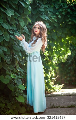 Beautiful girl in a long dress the color of mint walk on summer garden