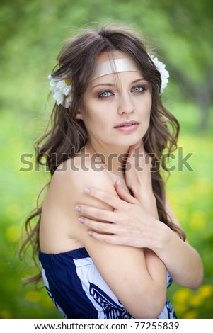 Portrait of a beautiful young woman with daisies in her hair, outdoors, park