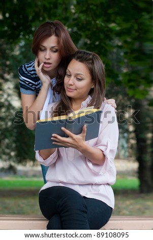 Two female students read the book, European, White, Caucasian