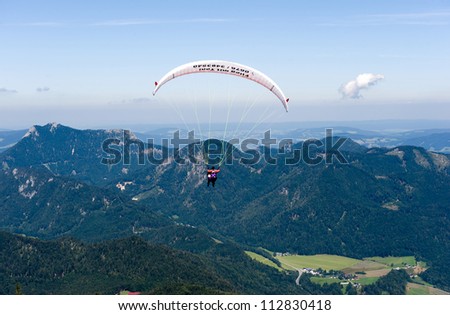 ST.GILGEN, AUSTRIA - AUG 18: A paraglider is flying to the city of St.Gilgen on Aug 18, 2012. The Zwolferhorn mountain is a popular paragliding spot by because of it\'s thermics.