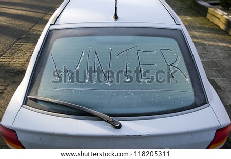 The word winter written on the frozen back window of a car