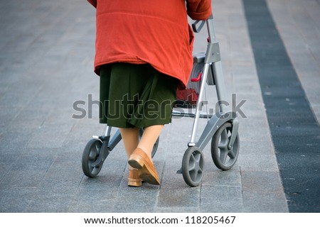 An elderly woman walking on the street with her walking frame