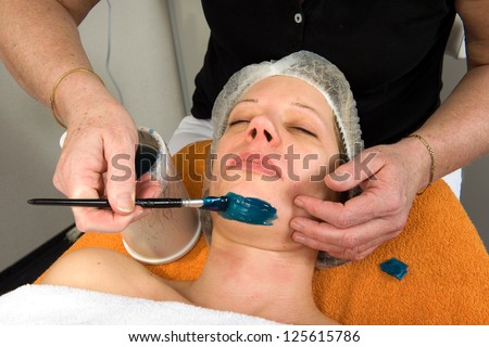 A woman\'s chin is being waxed in a beauty salon