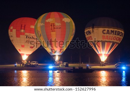 OLDENZAAL, THE NETHERLANDS - AUGUST 23: Three hot air balloons are glowing on the beach of a recreation pond, at a 4 days festival in the Netherlands, Aug 23, 2013.