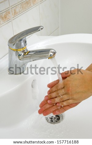 A woman is washing her hands in the bathroom