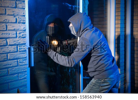 A burglar is looking through the window of a house