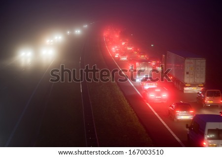 ENSCHEDE, NETHERLANDS - DEC 11: A convoy on a highway on a foggy december evening during rush hour in the Netherlands, december 11, 2013.