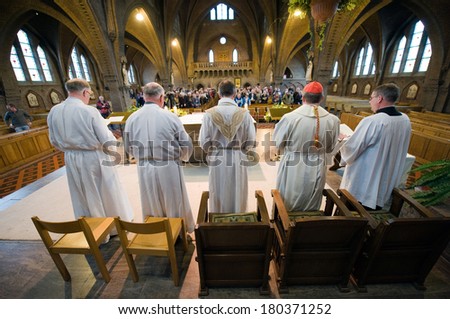 HENGELO, NETHERLANDS - APRIL 09: A priest, a cardinal (red cap) and their helpers are standing during a mass in the roman catholic \'Onze lieve Vrouwekerk\' church of Hengelo, April 09, 2012