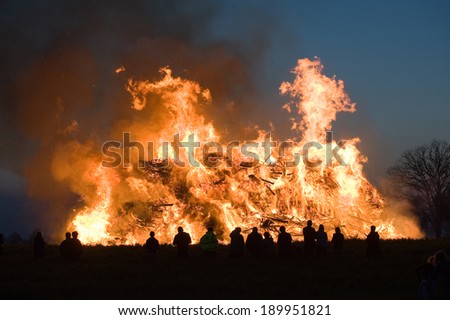 People are watching a huge bonfire, a tradition with easter in North-West Europe.