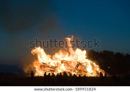People are watching a huge bonfire, a tradition with easter in North-West Europe.